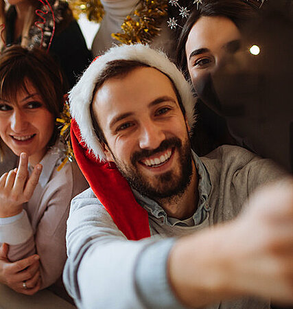 Mann mit Weihnachtsmütze macht Selfie 