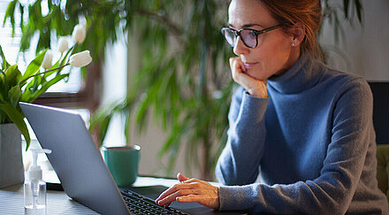 Frau mit Brille recherchiert am Laptop