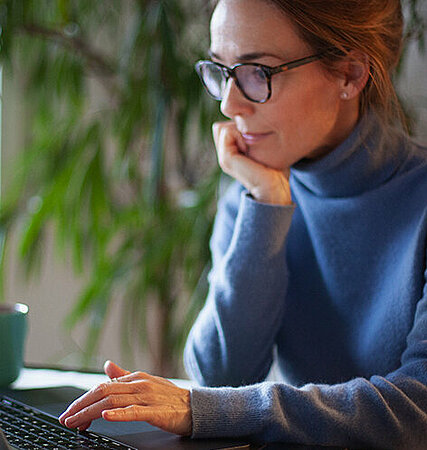 Frau mit Brille recherchiert am Laptop
