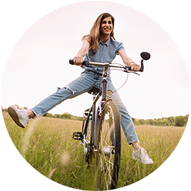 Junge Frau fährt Fahrrad auf einer Wiese