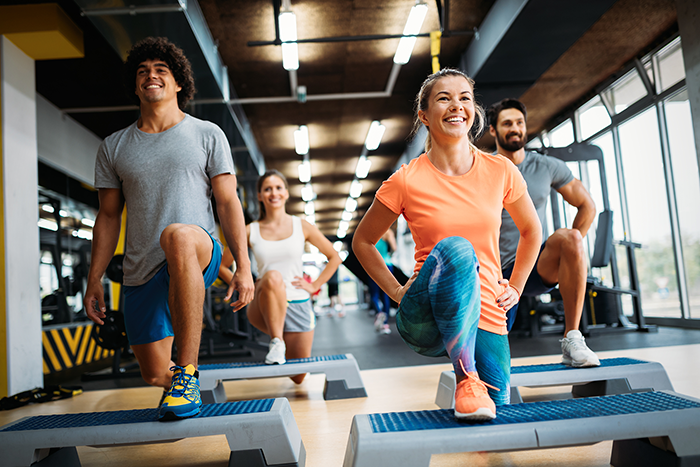 Vier Personen machen Step-Aerobic-Übungen im Fitnessstudio