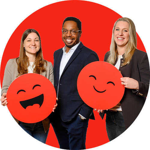 Diverse Edenred Mitarbeiter lächeln in die Kamera und halten rote Emojis